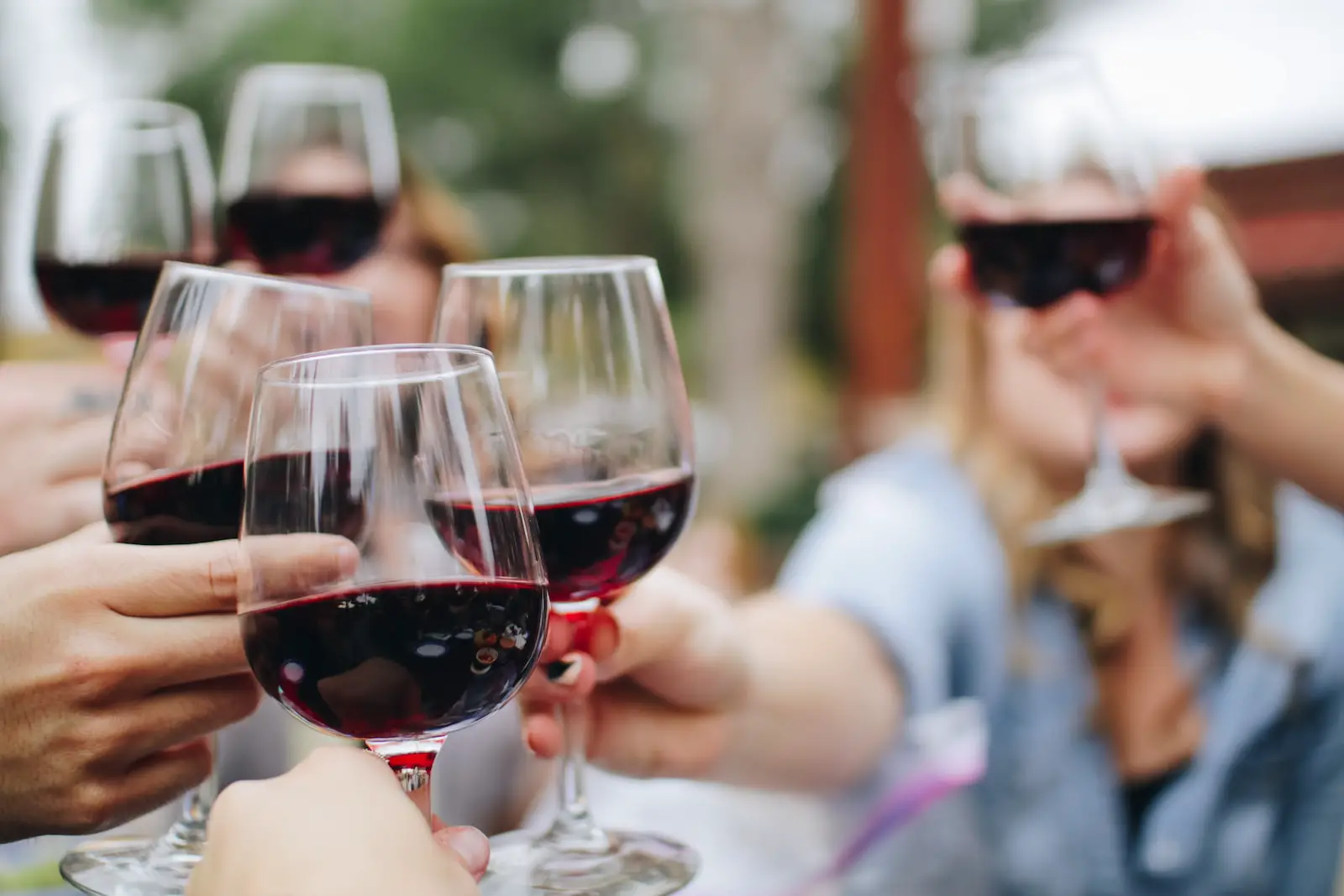 people tossing their clear wine glasses - how to start a wine tasting group